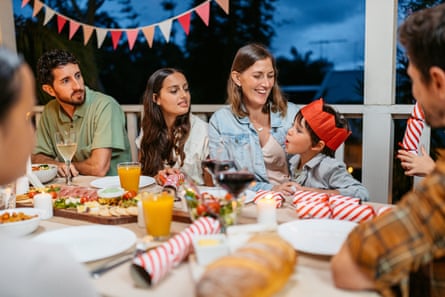 Young Family Exchanging Christmas Crackers During Christmas Dinner On The Patio Outdoors In Sydney In AustraliaYoung family exchanging Christmas crackers during Christmas dinner on the patio outdoors in Sydney in Australia.