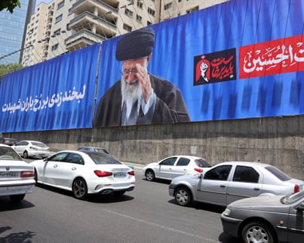 Three lanes of traffic beneath a large billboard featuring Khamenei