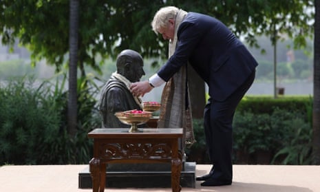 Boris Johnson drapes a ring of khadi cloth around a statue of Gandhi during his visit to the Gandhi ashram in Ahmedabad, India.