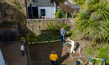 Peter and Sarah playing cricket in their garden with sons Oscar and Felix, with Chad and Clare Hudson looking over the wall