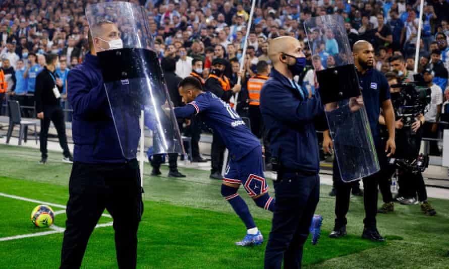 Security personnel carry riot shields to protect Paris Saint-Germain's Neymar from objects thrown by Marseille fans