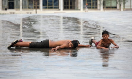 Children cool off in water on a square in Tirana, Albania.