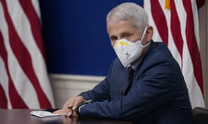 Anthony Fauci at a Covid briefing on 27 December. He wears a face mask and sits in front of an American flag.