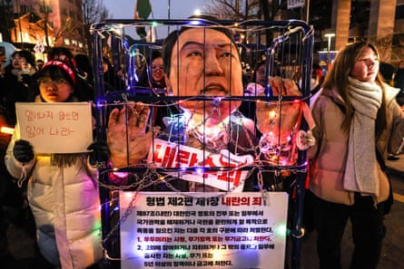Protesters in Seoul hold a chained effigy depicting Yoon Suk Yeol during a rally calling for his resignation, in December 2024.
