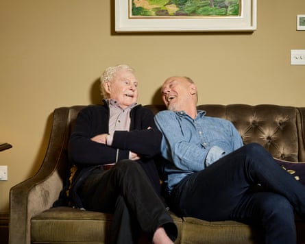 Jacobi and Clifford sitting on a couch, looking at each other and laughing