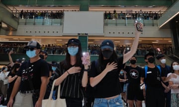 Masked protesters sing in a shopping mall.