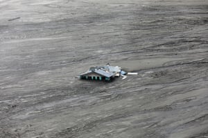 The roof of a home amid a streaking torrent of mud