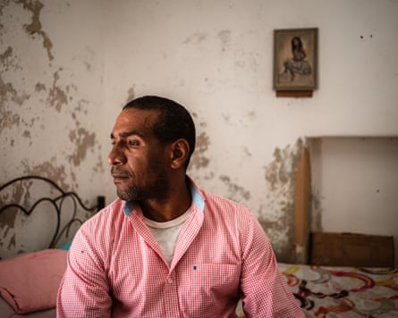 A man sits on a bed in a bedroom