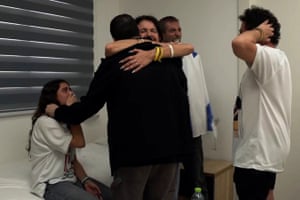 Guy Gilboa-Dalal, his back to the camera and wearing a black top, his hugged by a relative