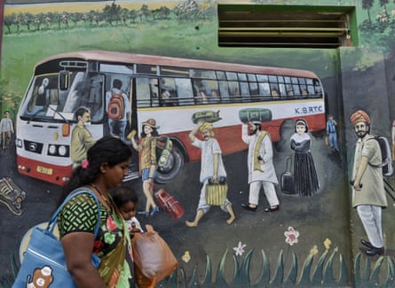 A woman with her child walks past an image of a bus in bangalore, india.