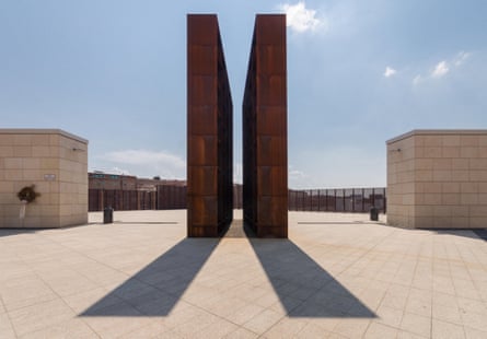 Two tall steel walls casting a shadow in a stone courtyard