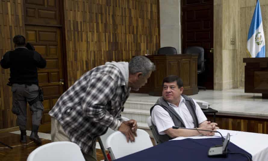 Former army officer Esteelmer Francisco Reyes Girón, sitting, talks with former paramilitary fighter Heriberto Valdez Asij during their trial for sex abuse in Guatemala City.