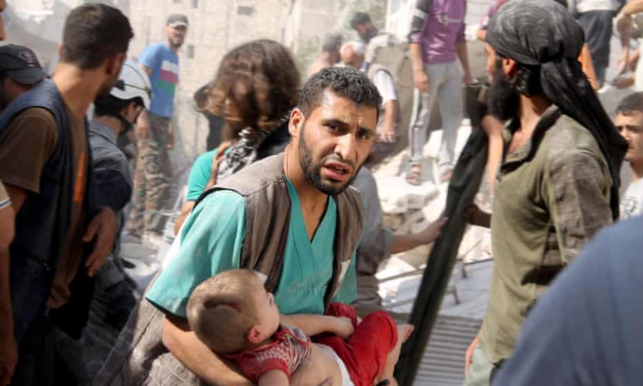 A Syrian man carries an injured child at the site of air attacks by Assad's forces on a residential area in Aleppo.