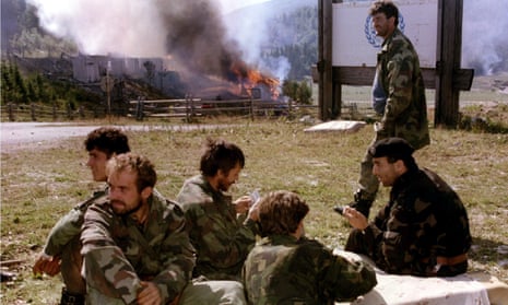 Bosnian Serb soldiers play cards in front of the burning Igman Hotel