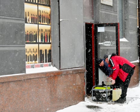 Employees refuel a power generator outside a shop during the blackout following Russian drones and missiles attacks in Kyiv.