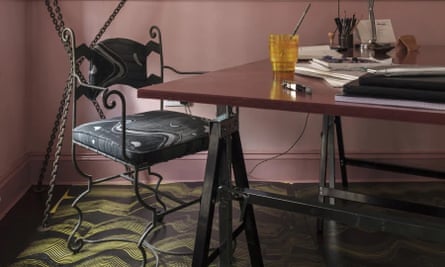 Scraped pattern on the floor under a wrought-iron framed chair at a tresle table with a lamp on it