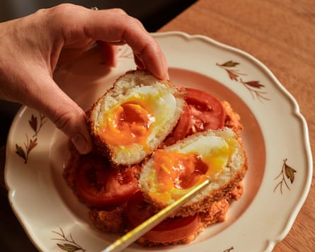 A meal with egg in it on a plate, with a hand holding it.
