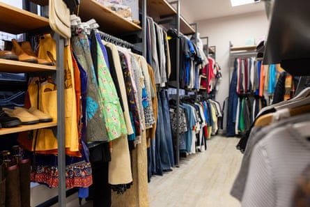 A wide shot of inside a charity shop located in Newcastle upon Tyne. There are multiple railings full of varied items of clothing and shoes.