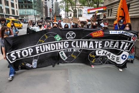 People in New York march with a sign saying 'Stop funding climate death' with Citi, TD, Wells Fargo. Bank of America, and Chase logos on it.