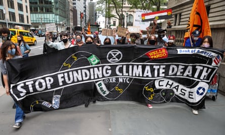 activists hold sign that says 'stop funding climate death'