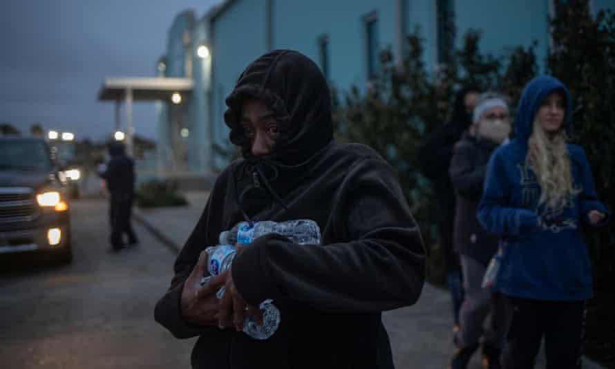 A woman carries bottled water she received from a warming center and shelter in Galveston.