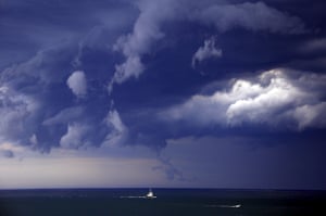 Boats head to shore as storm clouds move along the coast