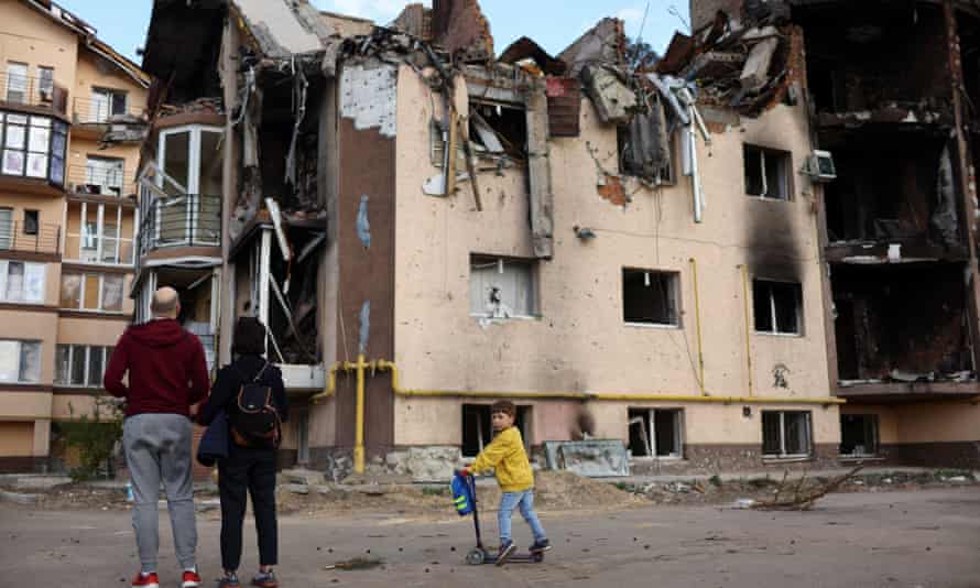 A boy rides a scooter in a bomb-damaged residential neighbourhood of Irpin, northern Ukraine.