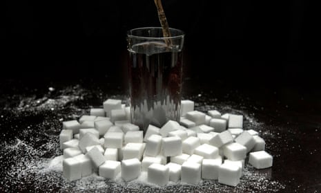 A cola drink surrounded by sugar cubes
