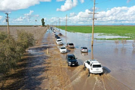 Cars detour on flooded Road 144 as both sides of highway 99 closed due to major flooding in Earlimart of Tulare county on Saturday as atmospheric river storms hit California.