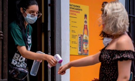 A restaurant hostess checks the temperature of a client with a digital temperature meter at the entrance of a restaurant in Old San Juan, July 20.