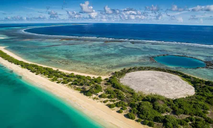 The Runit dome, a concrete sarcophagus filled with nuclear waste on Runit Island, beside a crater left by another nuclear test.