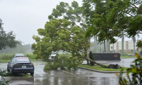 Gusts from Hurricane Ian begin to knock down small trees and palm fronds in a Florida hotel parking lot.