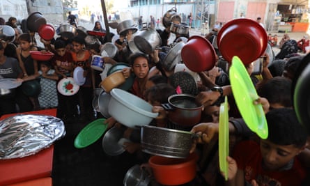 Palestinians in a crowd with bowls and plates