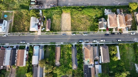 An aerial view of a road with built houses among vacant lots