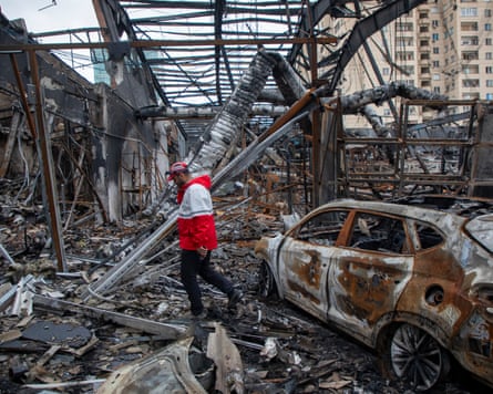 A worker with the Iranian Red Crescent Society walks through the rubble of a foreign car repair workshop that was destroyed during a joint US and Israeli attack.