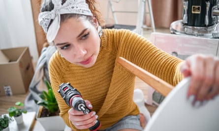 Young woman with a drill holding a wooden table