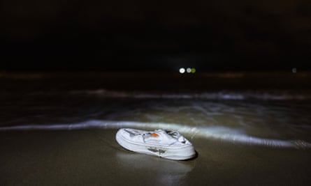 White trainer belonging to a migrant lying on the beach at Bleriot, northern France, at the water’s edge in the dark