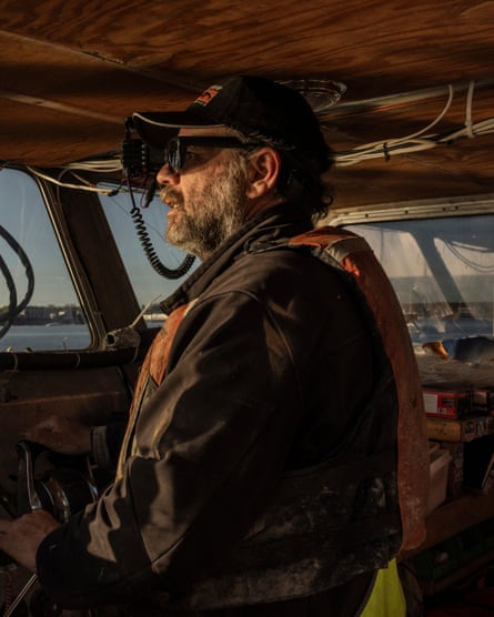 Tom Briggs, farm manager, in baseball cap and sunglasses, piloting a boat.