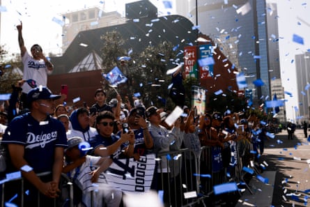 fans line a street amid blue and white confetti