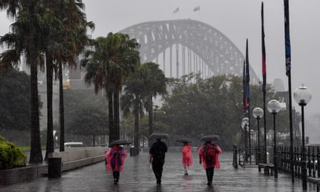 People walk in the rain near the Sydney Harbour Bridge.