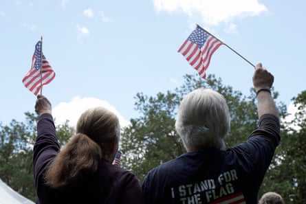 Two people stand holding small American flags