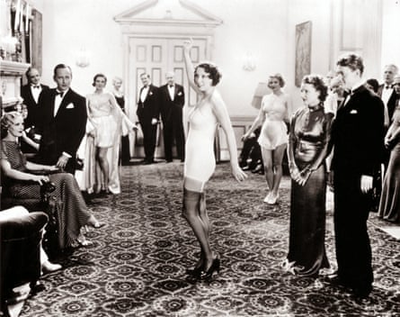 Men in black suits and ladies in long evening gowns watch a salon presentation, in 1925 New York.