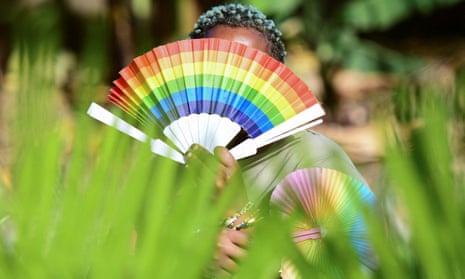 Quin Karala, a member of the LGBTQ+ community in Kampala, Uganda, holding a rainbow fan in front of her face.