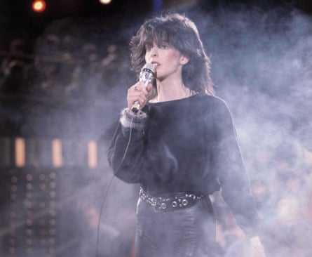Nena sings into a microphone, in a cloud of dry-ice smoke