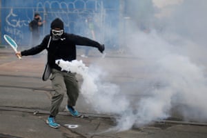 A protestor uses a tennis racket to return a teargas canister during a demonstration against the government’s proposed labour law reforms