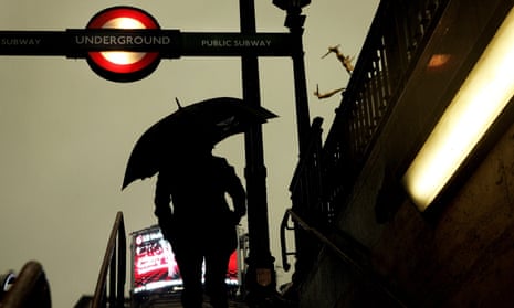 A person exits a London Underground station in heavy rain