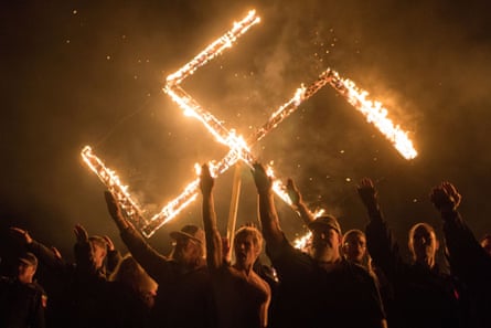 Supporters of the National Socialist Movement, a white nationalist political group, give Nazi salutes while taking part in a swastika burning in Georgia on 21 April 2018.