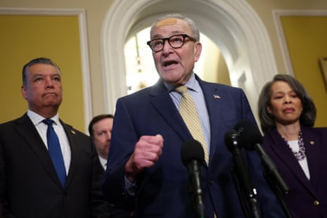 a man speaks into microphones while people stand behind him