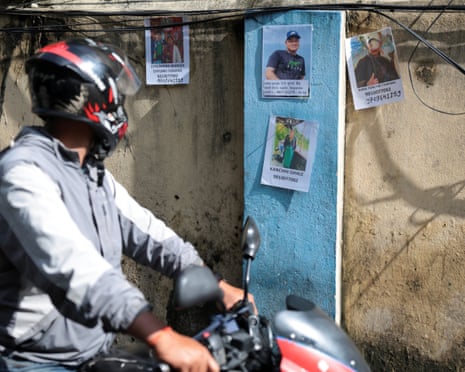 A man on a motorcycle looks at pictures of missing people at the Trauma Centre in Kathmandu, Nepal