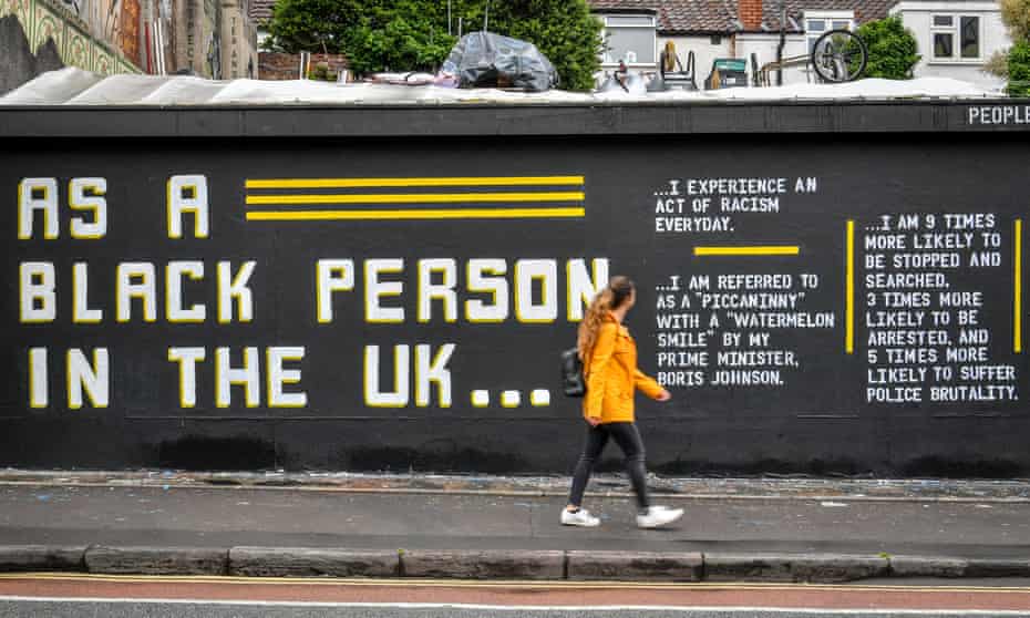 woman walks past graffiti art about Black Lives Matter on a wall in Bristol